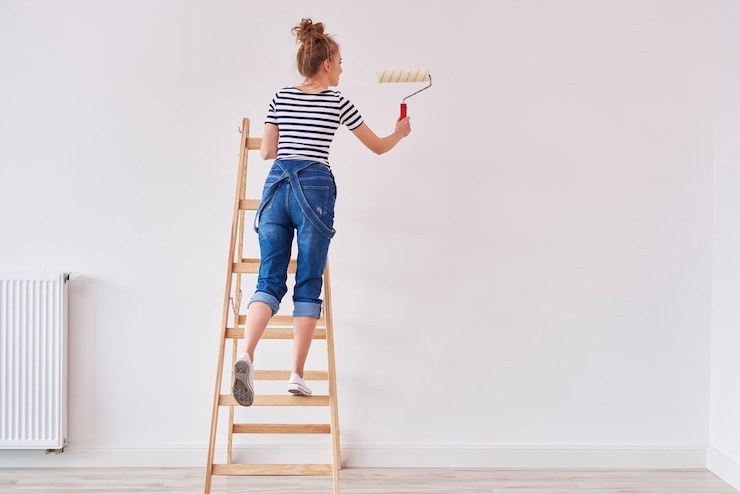 Free Photo rear view of woman with paint roller painting wall