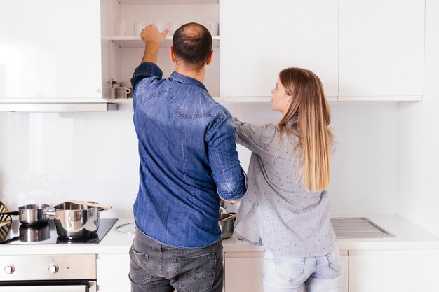 Rear view of a young couple taking glasses from the shelf