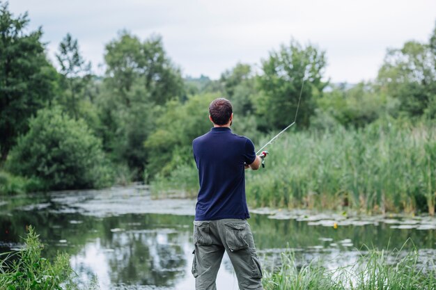 Вид сзади молодой человек, ловивший рыбу в озере