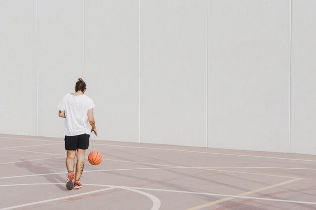 Rear view of a young man praticing basketball