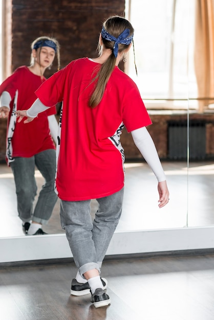 Free photo rear view of a young woman dancing in front of mirror