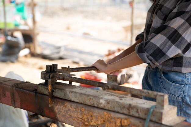 Rebar bending by worker on rusty jig in construction site