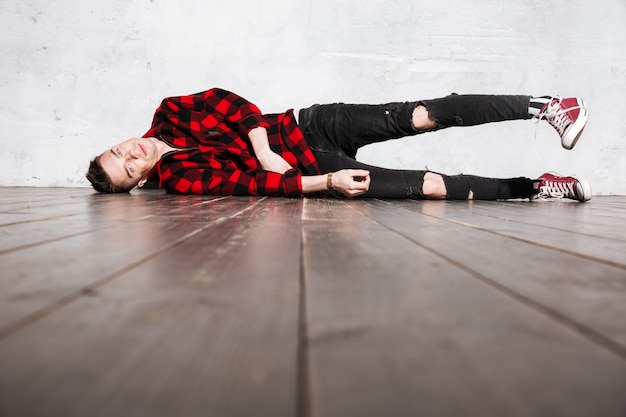 Free photo rebel man in plaid shirt lying on the floor