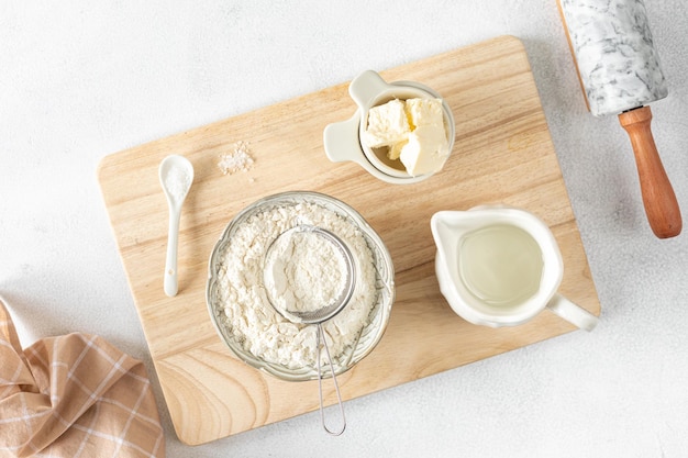 Recipe step 1 Ingredients for home baking The concept of baking is a marble rolling pin flour butter water on a white background Top view flat lay