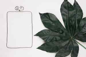 Бесплатное фото Прямоугольная рамка возле зеленого большого листа на белом фоне