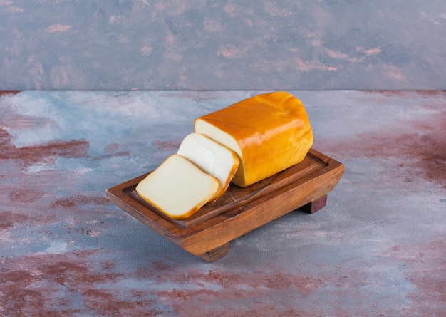 Rectangular sliced cheese on a board on the marble surface