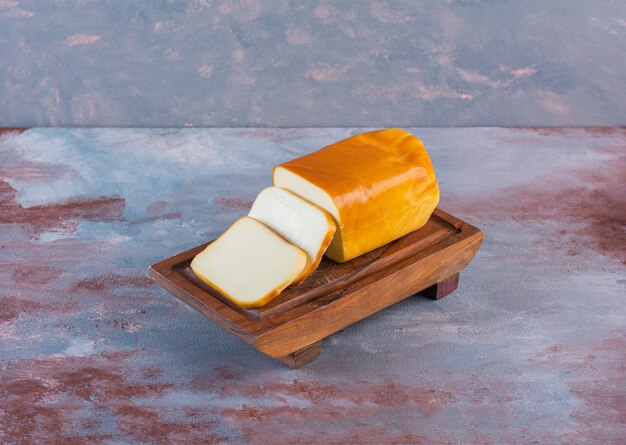 Rectangular sliced cheese on a board on the marble surface