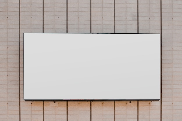 Rectangular white blank billboard on striped wall