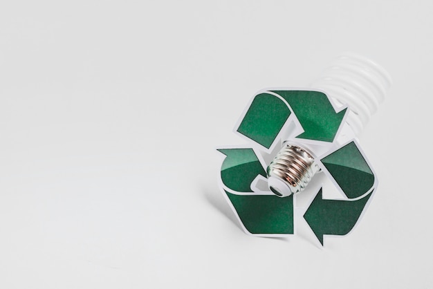 Recycle icon on compact fluorescent light bulb against white background