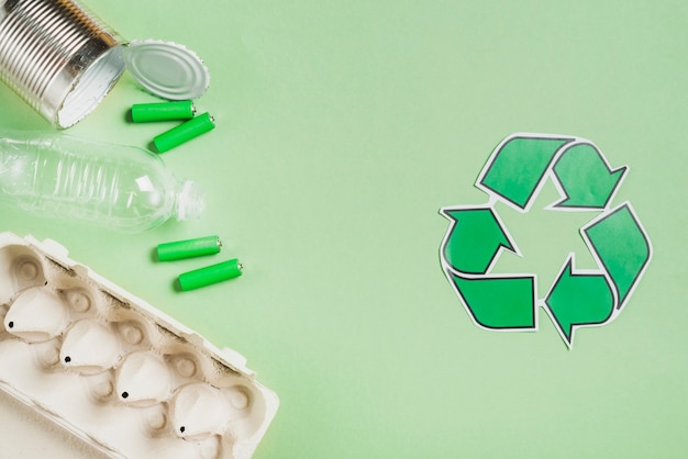 Recycle icon with waste products on green background