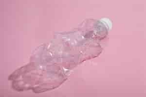Foto gratuita bottiglia di plastica riciclata su sfondo rosa