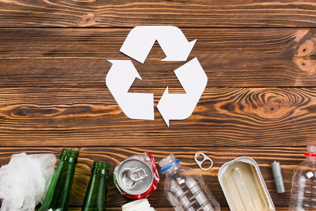 Recycling icon and trash on wooden background