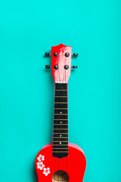 Бесплатное фото Красная акустическая классическая гитара на фоне бирюзы
