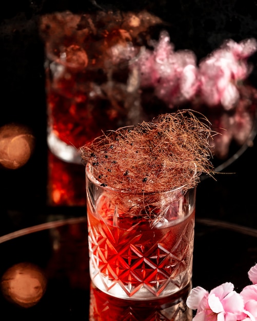 Red alcohol drink with corn hairs decoration and flowers.