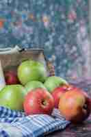 Бесплатное фото Красные и зеленые яблоки, изолированные на синем проверенном полотенце.