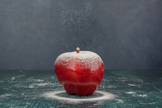 Red apple decorated with powder on blue surface