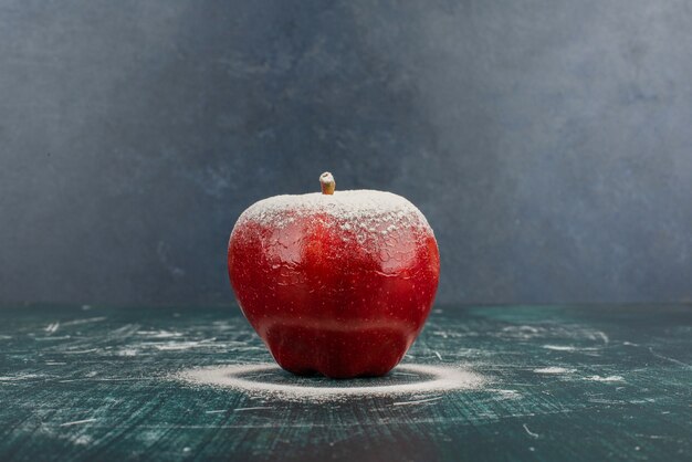 Red apple decorated with powder on blue table.