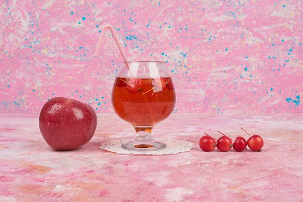 red apples and cherries with a glass of juice.