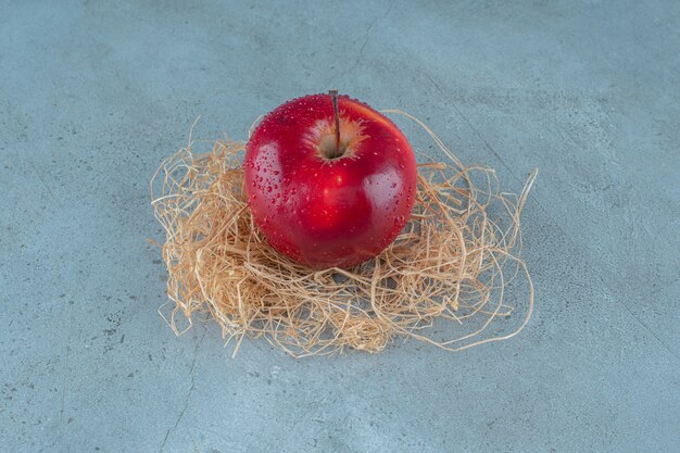 Красные яблоки на сухой соломе, на мраморном фоне. Фото высокого качества