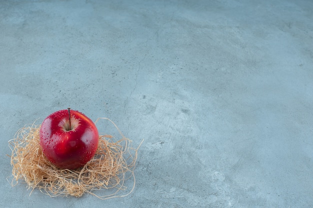 대리석 배경에 마른 짚에 빨간 사과. 고품질 사진