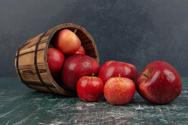 Red apples falling out of bucket on marble table