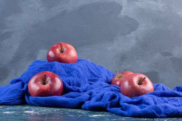 Red apples isolated on blue surface.