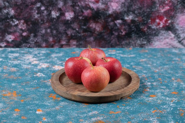 Красные яблоки, изолированные на деревянной доске.
