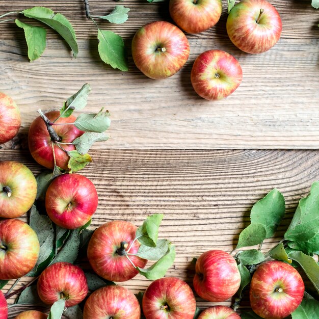 Red apples and leaves top view on wooden table