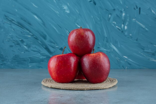 대리석 배경에 삼발이에 빨간 사과.