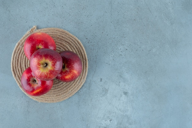 Red apples on a trivet , on the marble table. 