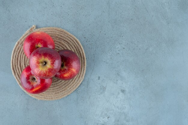 大理石のテーブルの上にある、トリベットの上の赤いリンゴ。