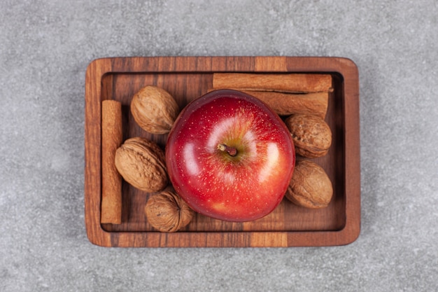 木​の​板​に​赤い​リンゴ​、​クルミ​、​シナモン​スティック