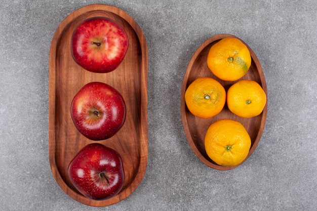 Free photo red apples with sweet tangerines on a wooden board