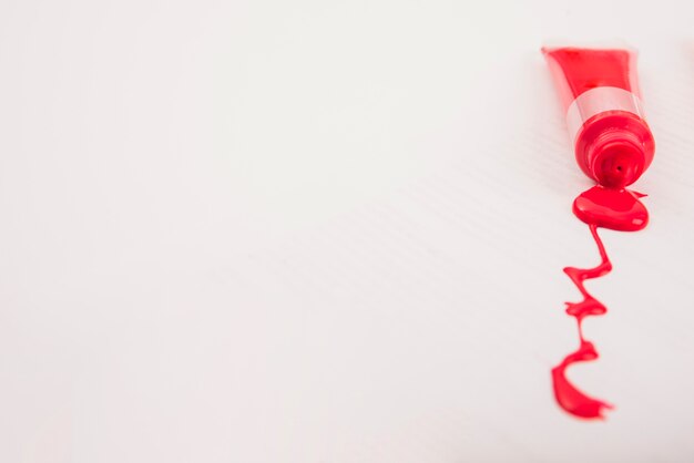 白い背景の上に絞った赤いアーティストカラーペイントチューブ