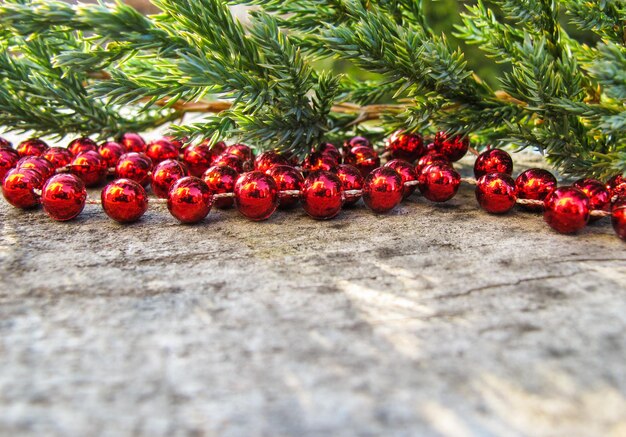 Red beads and conifer branches on a background of rustic wood with snow in sunny day space to copy