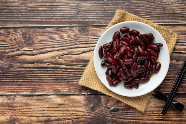 Foto gratuita fagiolo rosso bollito nel posto piatto bianco sul pavimento di legno