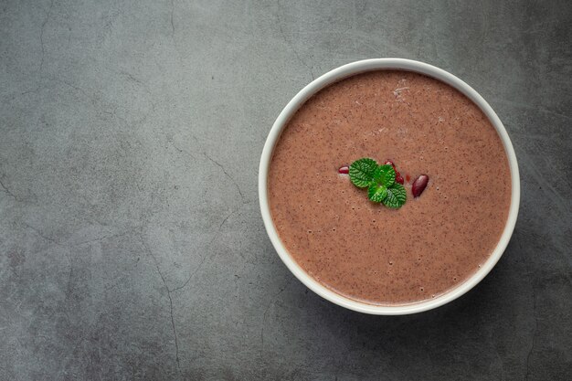 Горячий суп из красной фасоли в белой миске поставьте на темный пол