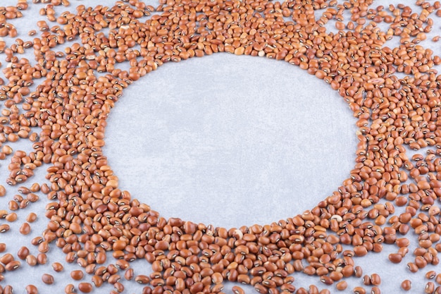 Red beans scattered around an empty circular space on marble surface