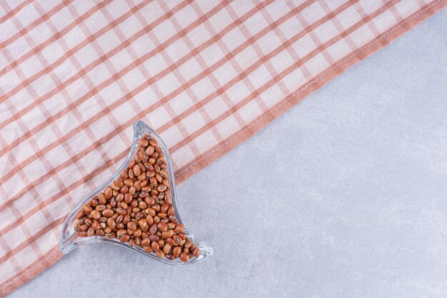 Red beans in a small, triangular dish on tablecloth, on marble surface