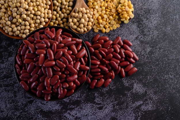 Free photo red beans in a wooden bowl on the black cement floor.