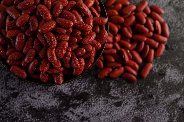 Free photo red beans in a wooden bowl and with water sprayon the black cement floor.