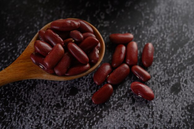 Red beans in a wooden spoon on the black cement floor.