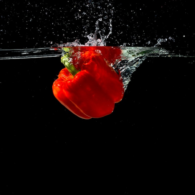 Red bell pepper falling in clean water