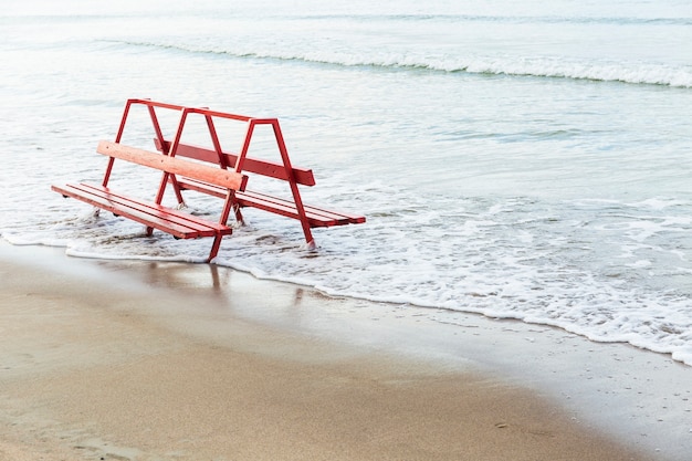 Foto gratuita banco rosso vicino all'acqua di mare