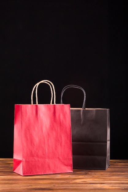 Red and black paper bag on wooden surface against black backdrop