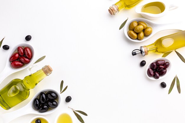 Red black yellow purple olives in spoons with oil bottle