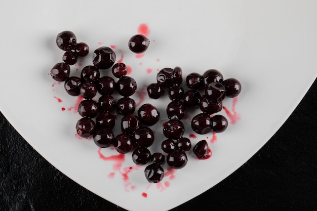 Red blackcurrant confiture in a white plate on black.