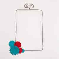 Free photo red and blue flower on the corner of wired rectangular frame against white backdrop