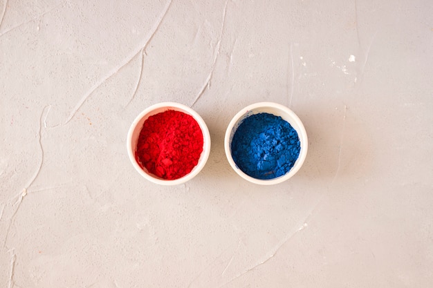 Free photo red and blue holi colored powder in the white bowl on backdrop