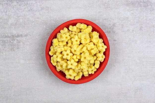 Red bowl full of delicious corn flakes on stone.